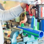 Junger Mann arbeitet in einer Werkstatt an Rohren. Als Stanz- und Umformmechaniker/in bist du ein echter Tüftler.