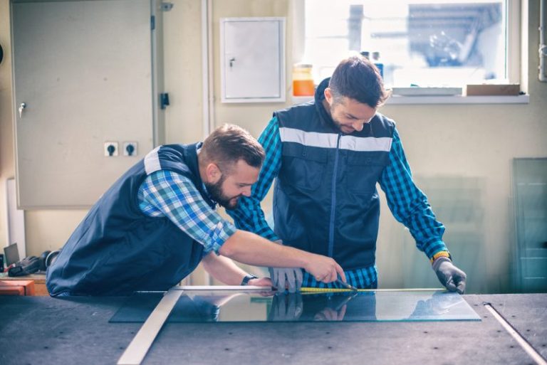 2 Männer schneiden eine Glasplatte. Glaser sind, unabhängig in welcher Fachrichtung sie sich befinden, in einer vielfältigen Auswahl verschiedener Branchen einsetzbar. Beruf: Glaser/in